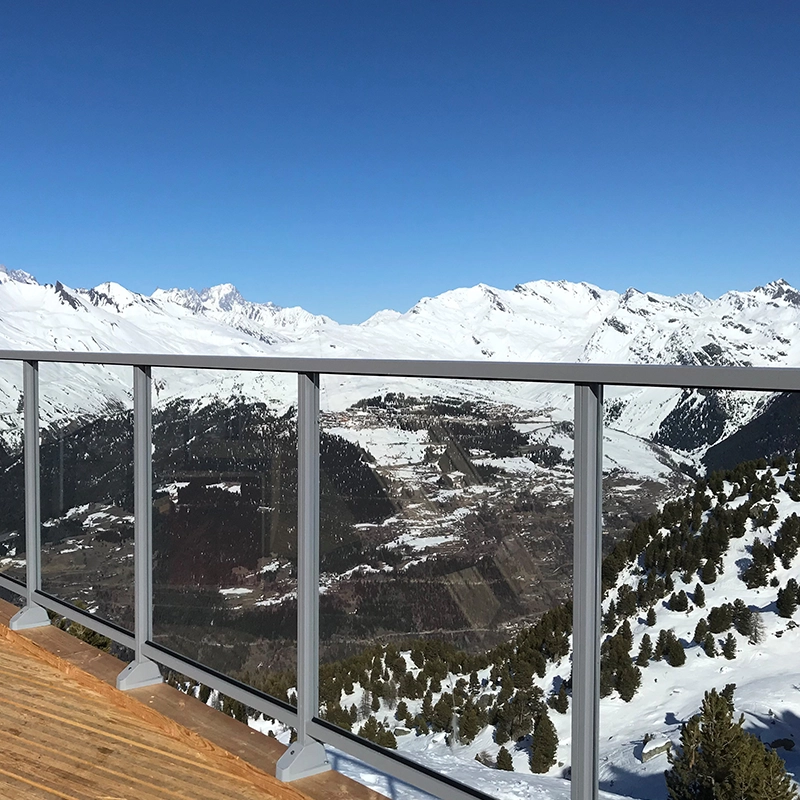 Garde-corps en verre et aluminium, gris clair, avec une vue sur la montagne.