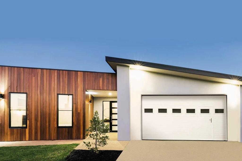 Une porte de garage blanche sectionnelle avec un portillon intégré.