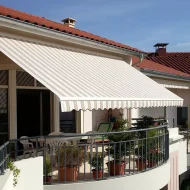 Un storebanne sur un balcon, motif rayé blanc et marron.